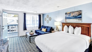 Une chambre d’hôtel avec un grand lit, un canapé, une petite table avec une lampe et un tableau au mur.