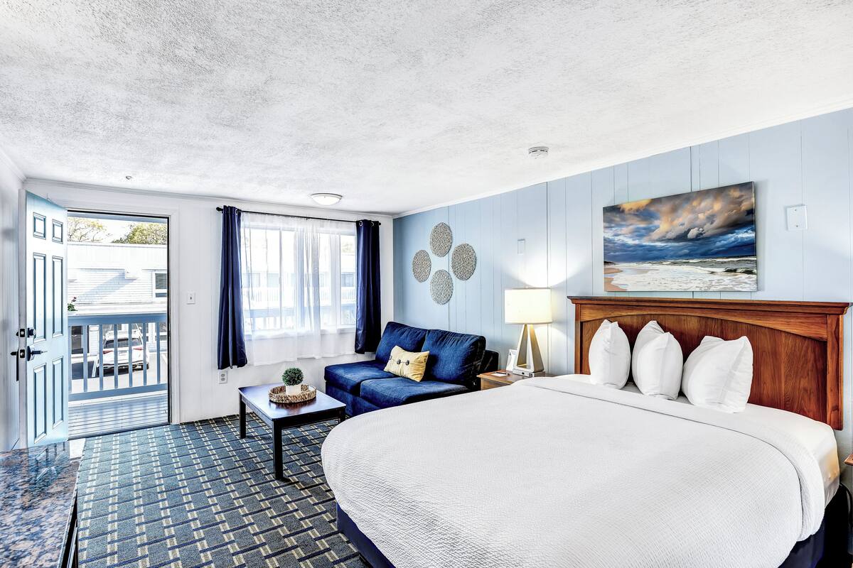 Une chambre d’hôtel avec un grand lit, un canapé, une petite table avec une lampe et un tableau au mur.