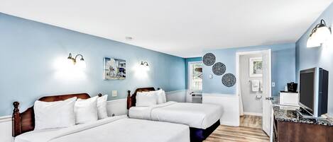 Une chambre avec deux lits, une télévision et une salle de bain visible à travers une porte ouverte.