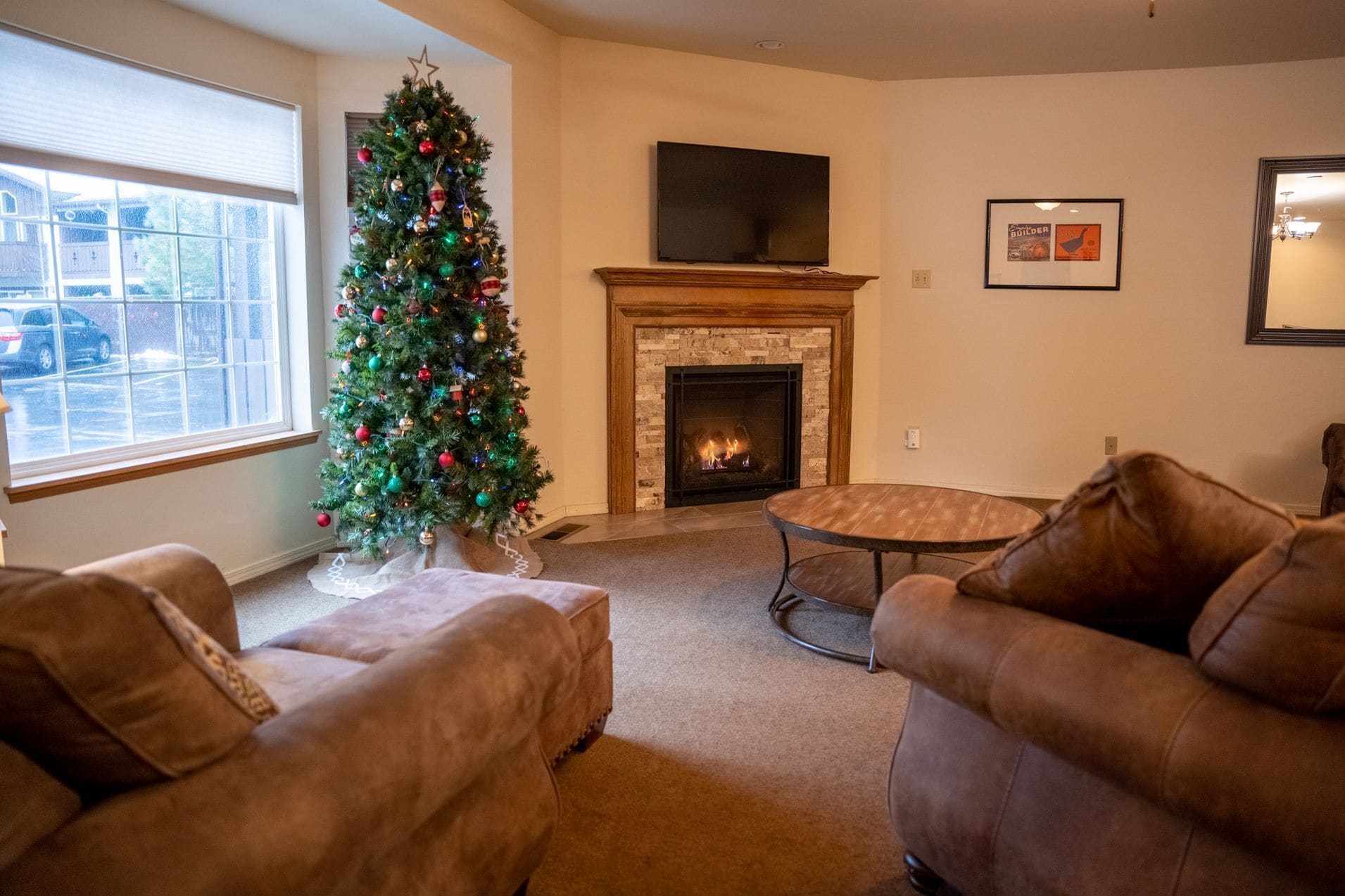 A living room with a fireplace, a Christmas tree, and leather sofas.
