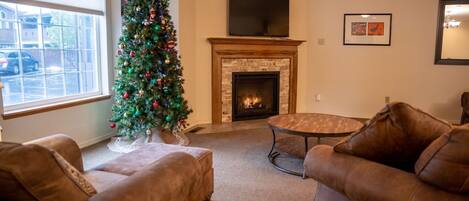 A living room with a fireplace, a Christmas tree, and leather sofas.
