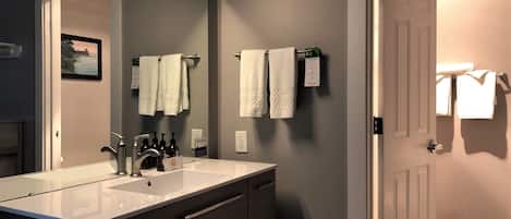 A bathroom with a double sink, a mirror, and two towels hanging on the wall.