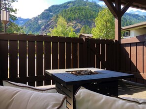 A patio with a table and chairs, a fire pit, and a view of a mountainous landscape. - Blue Elk Inn (Leavenworth)