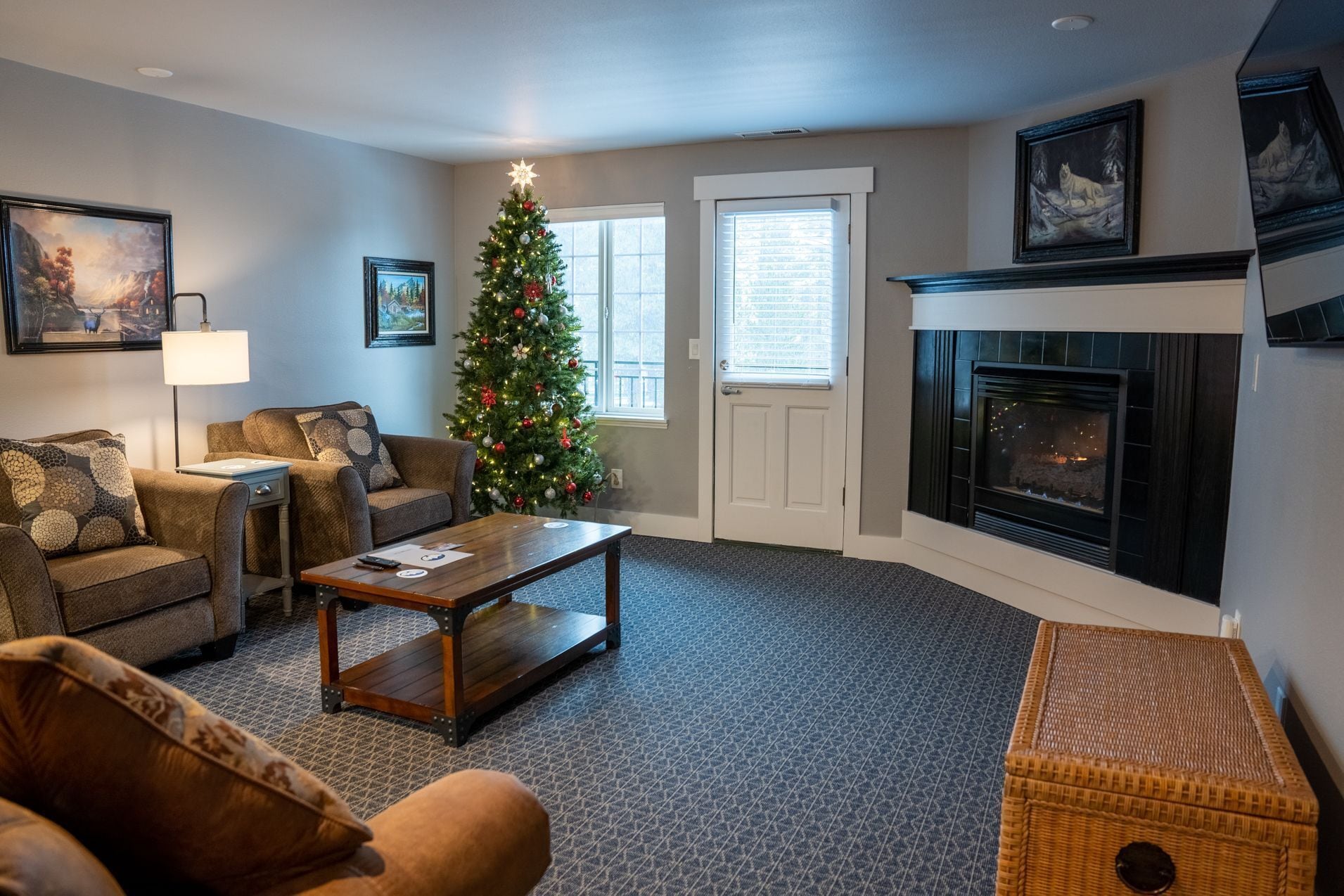A cozy living room with a fireplace, a Christmas tree, and comfortable seating.