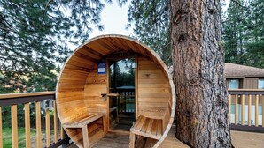 Una casetta sugli alberi in legno con ingresso circolare, integrata in un grande albero, con una panca e un tavolino all'interno.