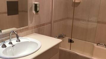 A bathroom with a sink, mirror, and shower.