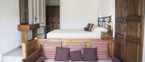 Un dormitorio con una cama de madera, una mesita de noche, un aparador y un espejo.