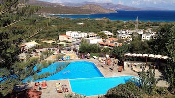 Una piscina al aire libre, sombrillas, sillones reclinables de piscina