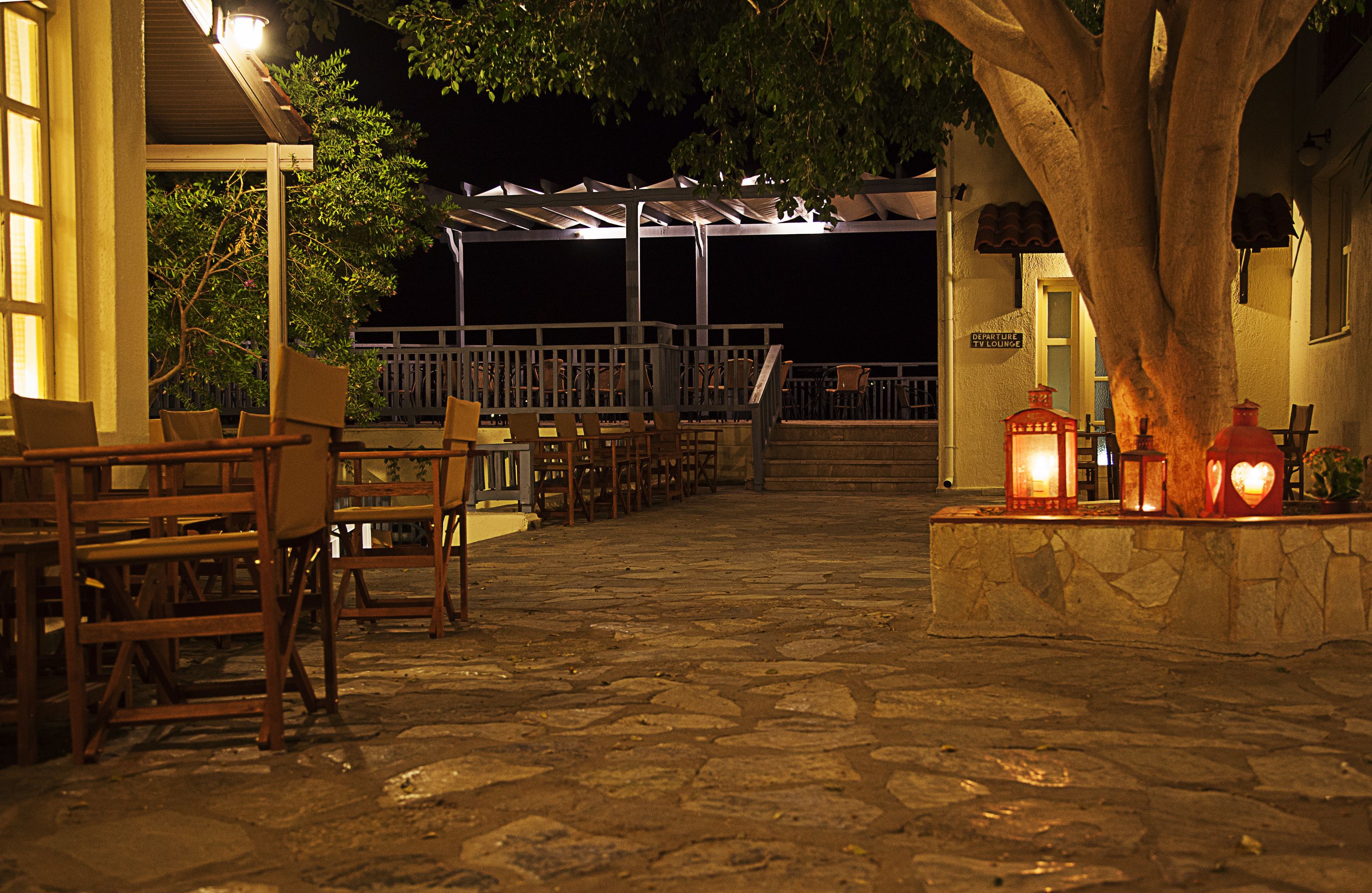 Un patio al aire libre con suelo de piedra, muebles de madera y faroles.