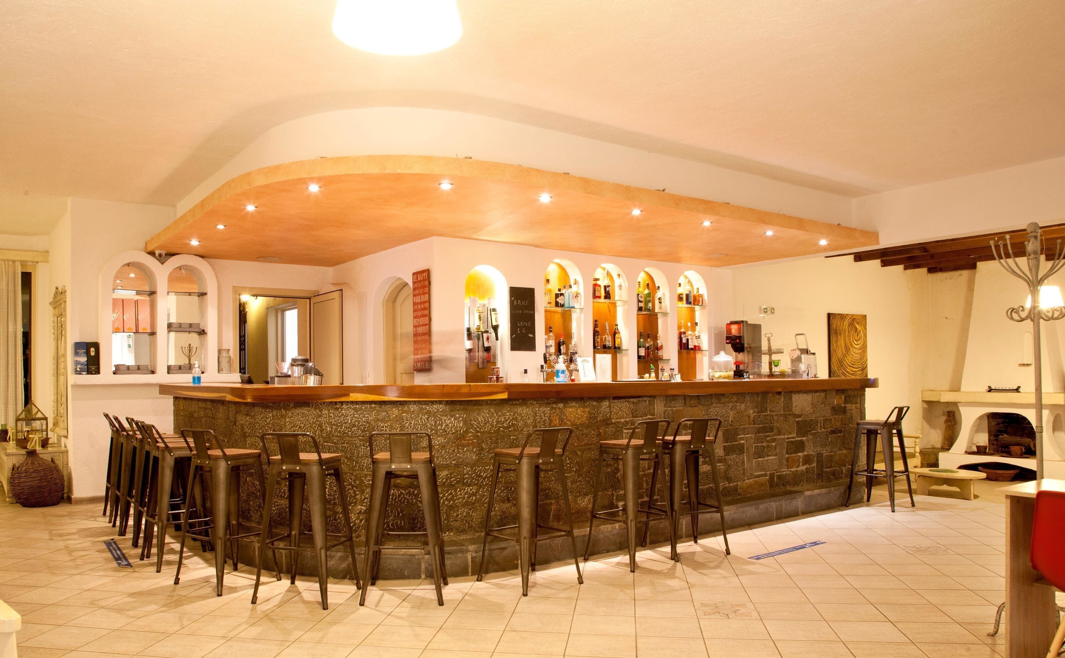 A bar area with a stone counter and multiple stools.
