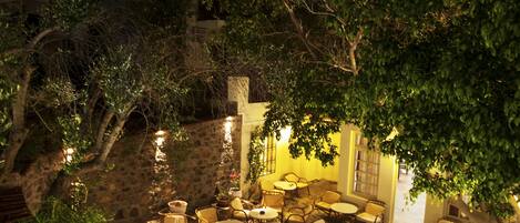 An outdoor patio area with stone flooring, wicker furniture, and ambient lighting.