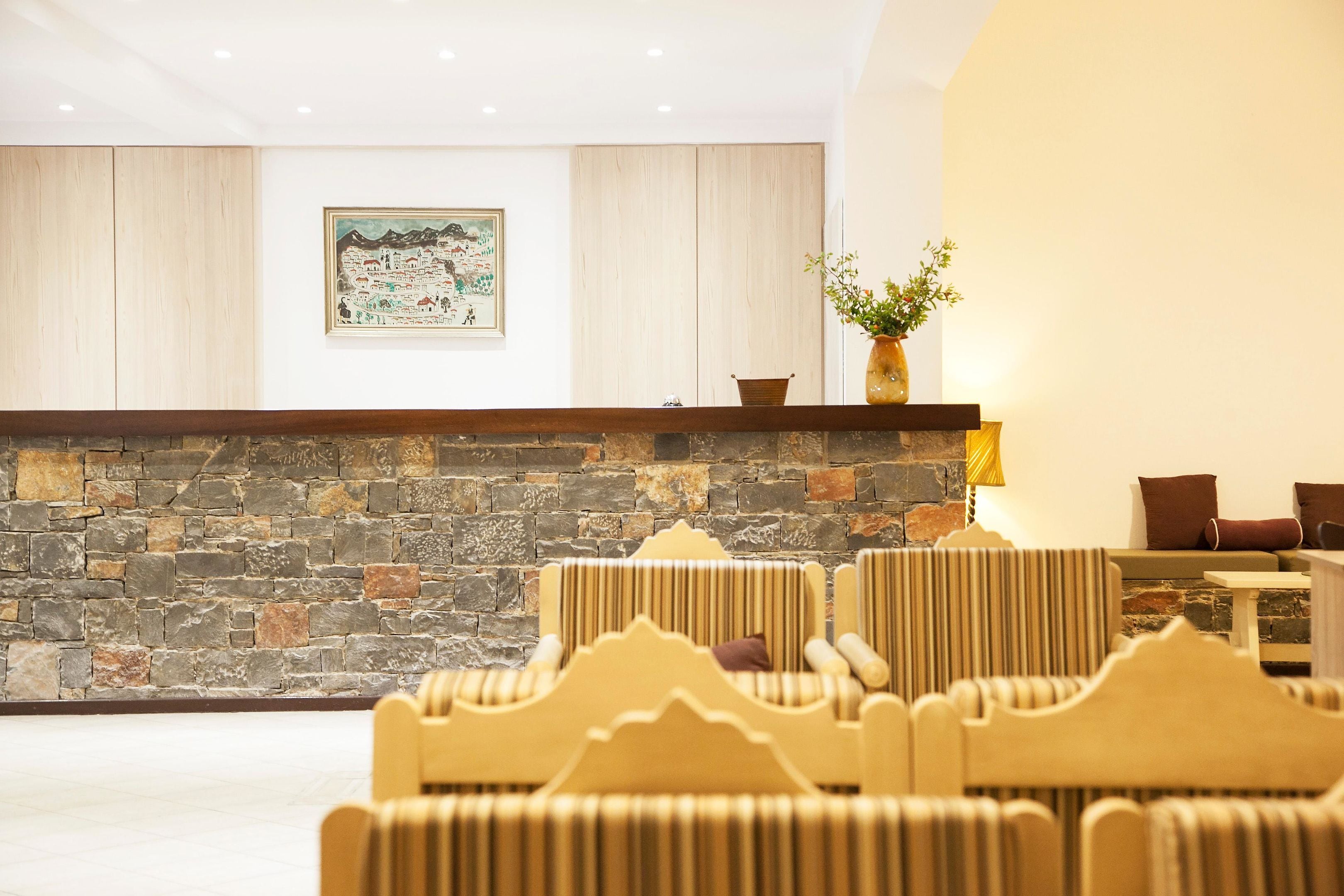 Un vestíbulo con pared de piedra, un mostrador de recepción y varias sillas tapizadas.