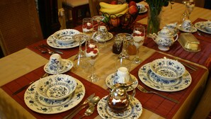 A dining table set with blue and white patterned plates, silverware, and a silver teapot. - Gingerbread Manor (Montreal)