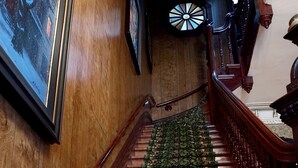 A wooden staircase with a floral carpet, a wooden handrail, and a wall-mounted picture frame. - Gingerbread Manor (Montreal)