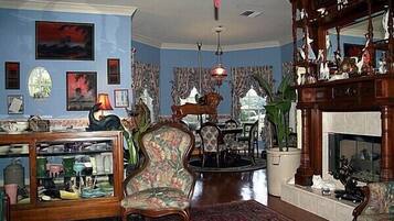 A traditional living room with a fireplace, a dining area, and a blue wall with artwork.
