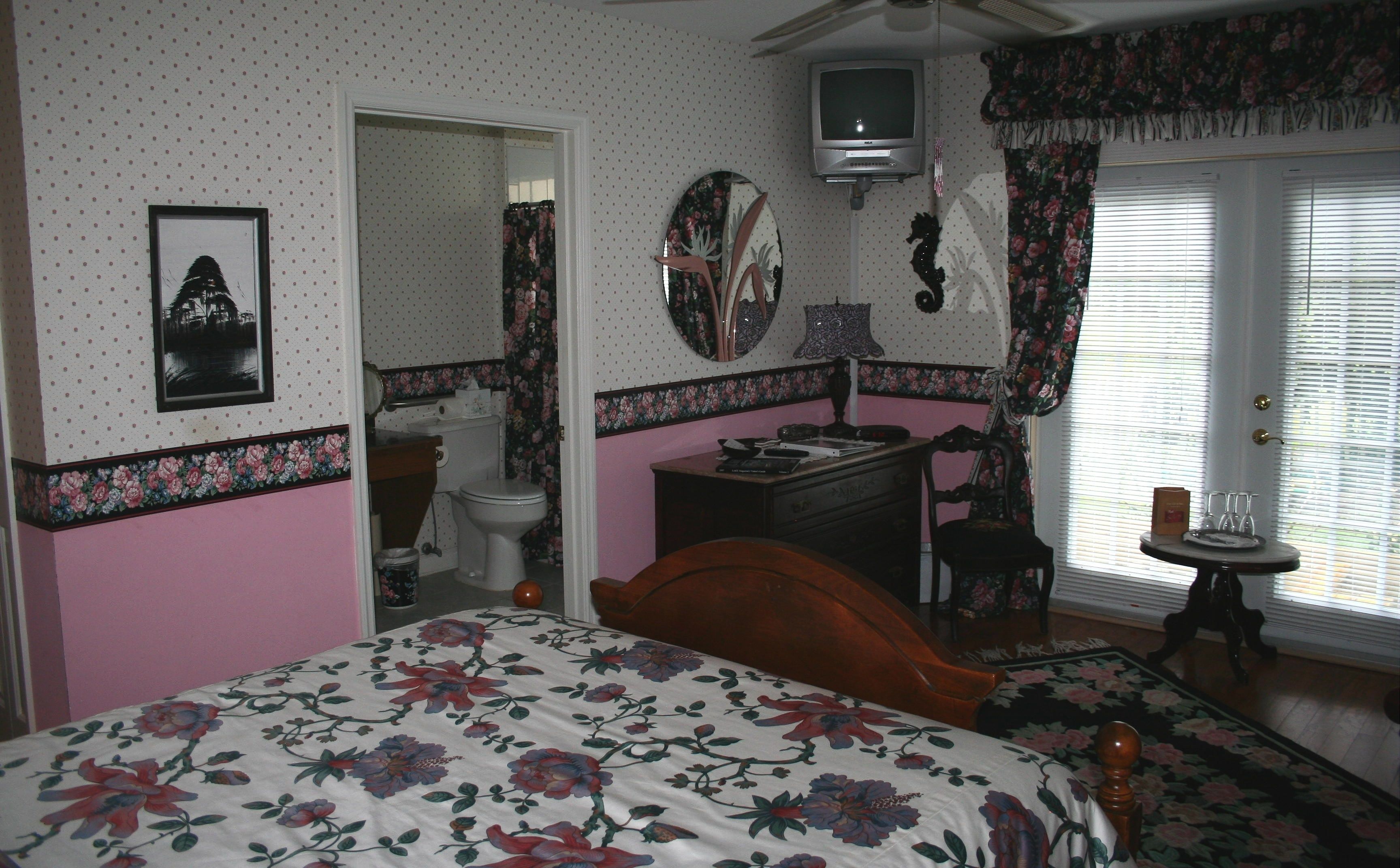 Un dormitorio con cama, cómoda, espejo y televisor.