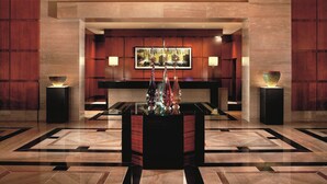 A lobby with a reception desk, a large framed artwork above it, and two decorative vases on stands. - The Ritz-Carlton, Charlotte (Charlotte)