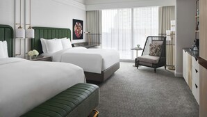 A hotel room with two beds, a green sofa, a small table with a lamp, and a view of the city through large windows. - The Ritz-Carlton, Charlotte (Charlotte)