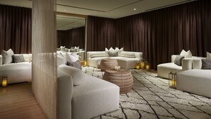 A modern living room with a large mirror, white sofas, and round wooden side tables. - The Ritz-Carlton, Charlotte (Charlotte)