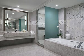 A modern bathroom with a large mirror, granite countertops, a bathtub, and a green accent wall. - The Ritz-Carlton, Charlotte (Charlotte)