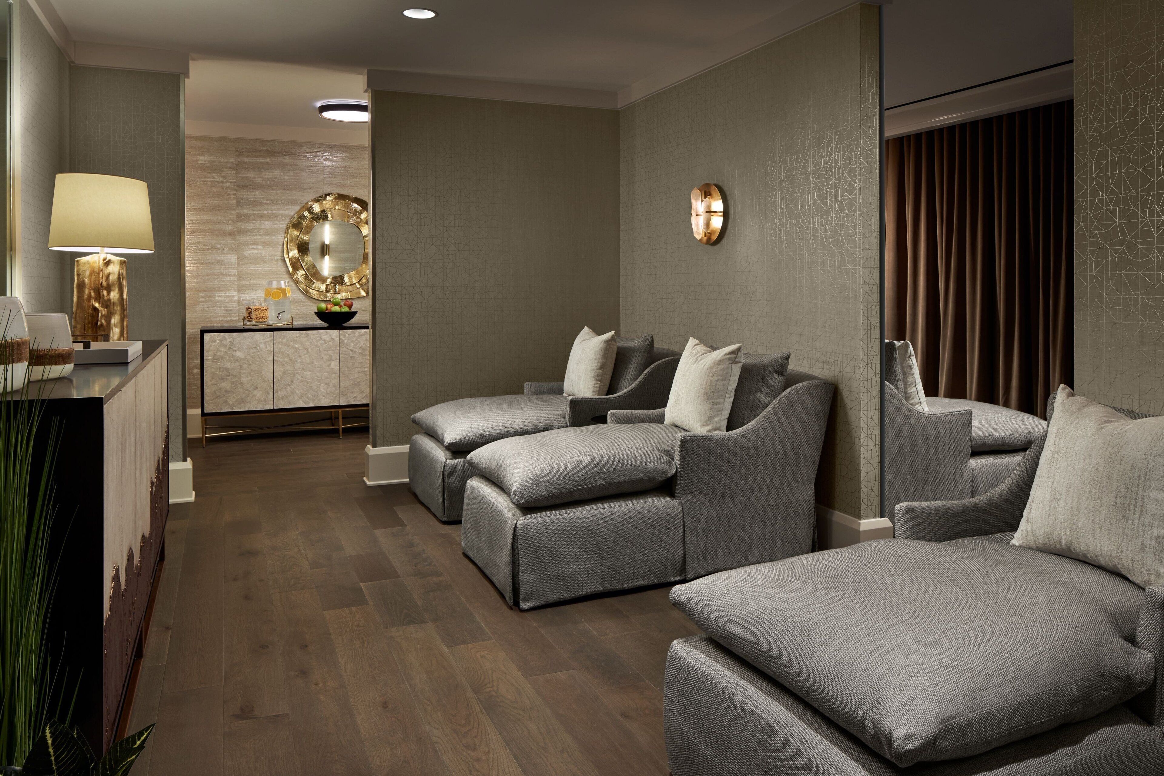 Un área de spa moderna con sofás grises, una mesa de masaje y un mostrador de recepción.