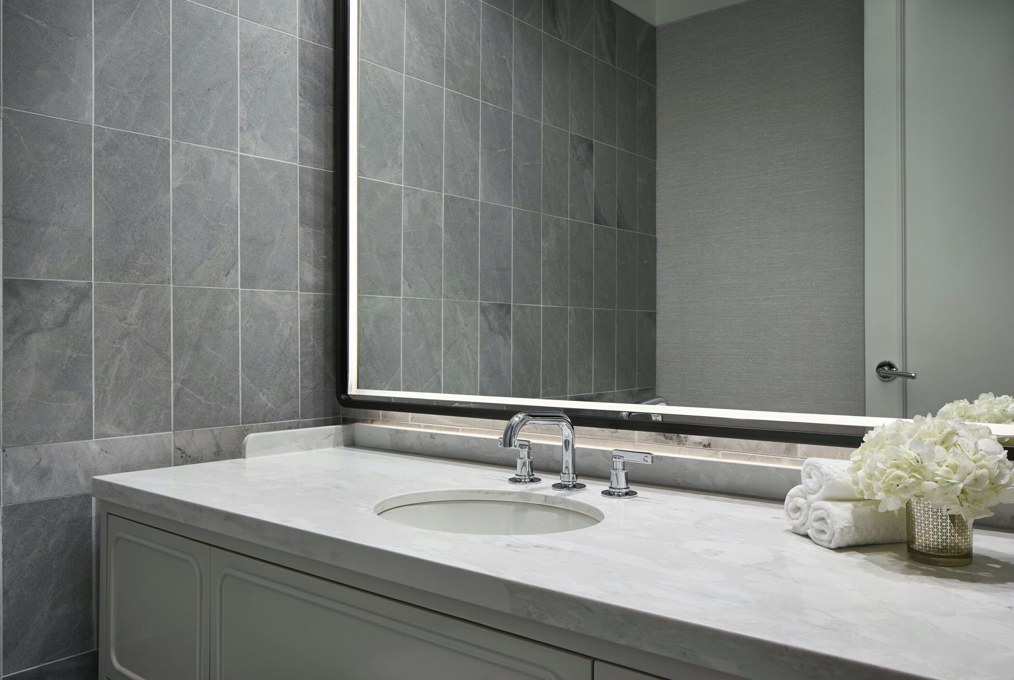 Un baño con un espejo grande, un lavabo y un perchero con toallas dobladas.
