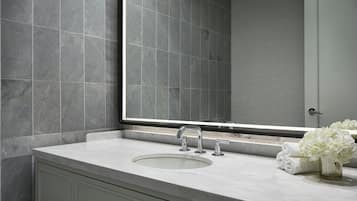 Un baño con un espejo grande, un lavabo y un perchero con toallas dobladas.