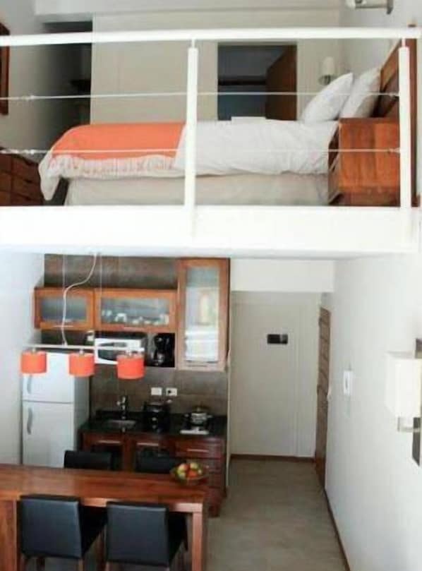 A compact studio apartment with a kitchenette, a dining area, and a sleeping area with a bed.