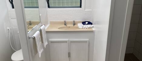 Et lille badeværelse med toilet, håndvask og skab.