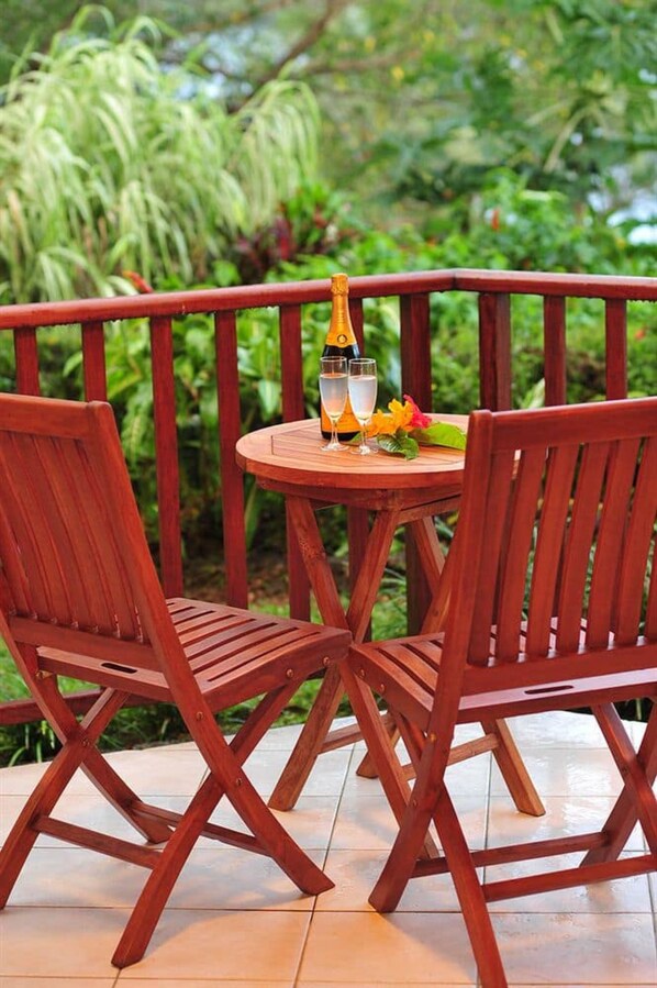A wooden outdoor table with two chairs, a bottle, and a glass of water. - Poppys On The Lagoon (Port Vila)