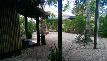 Un espacio al aire libre cubierto con un camino de grava, columnas de bambú y plantas en macetas.