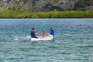 Una pequeña embarcación con tres personas en aguas tranquilas, rodeada de abundante vegetación.