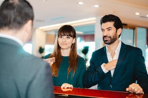 Un comptoir d’accueil où se tiennent debout un homme et une femme.