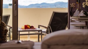 Habitación de hotel con balcón, una mesa de comedor con fruta y un vaso de jugo, y una cama con almohadas.