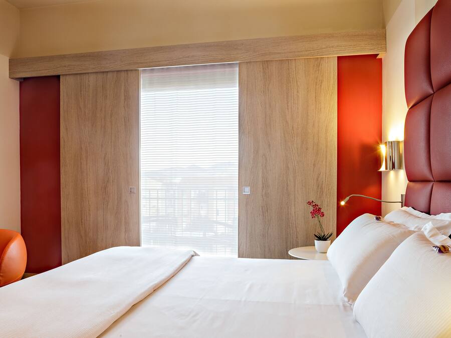Una habitación de hotel con una cama grande, una mesita con una lámpara y una silla.