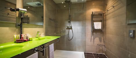 A modern bathroom with a green sink, a glass shower enclosure, a white toilet, and a towel rack.