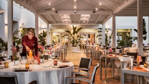 Un comedor amplio con mesas redondas, velas y plantas en macetas.