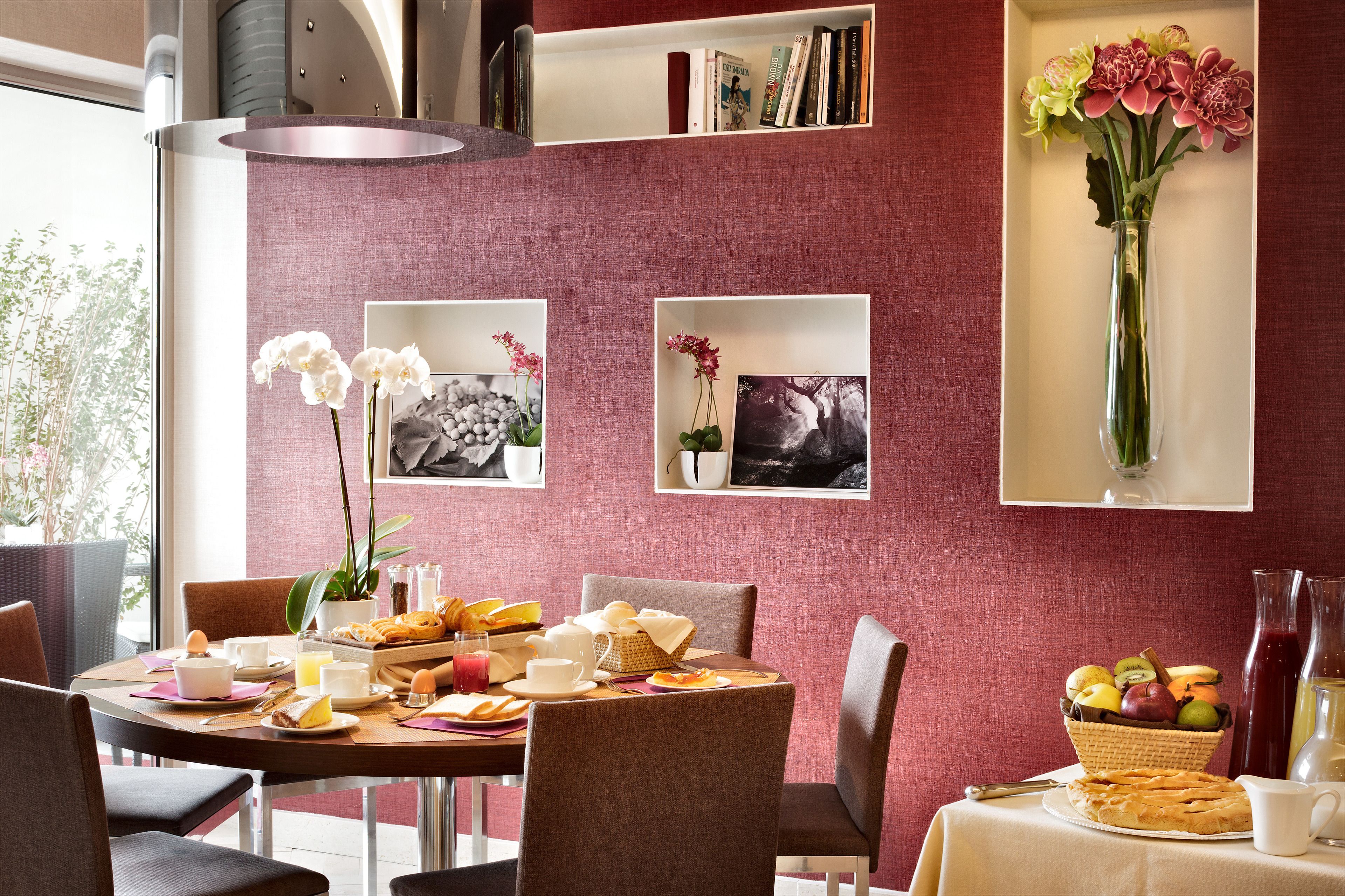 A breakfast setting with a table set for four, including plates of food, cups, and a vase of flowers.