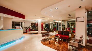 A modern lobby with a reception desk, seating area, and glass doors leading to other rooms.