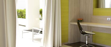 Una habitación de hotel moderna con una cama grande, un escritorio con una silla y vistas al exterior.