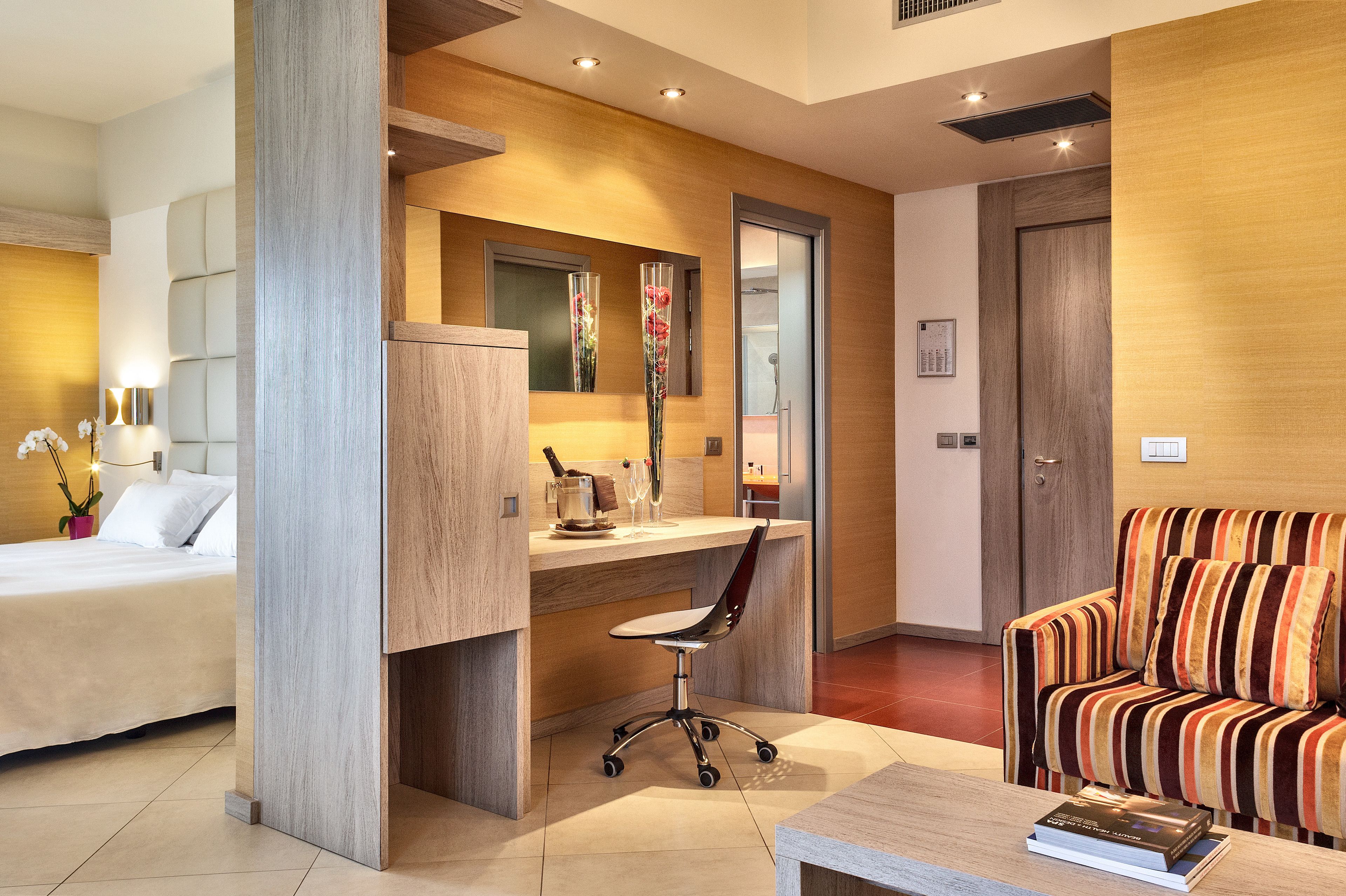 Una habitación de hotel moderna con una cama, un escritorio con una silla, un sofá a rayas y una mesita de centro.
