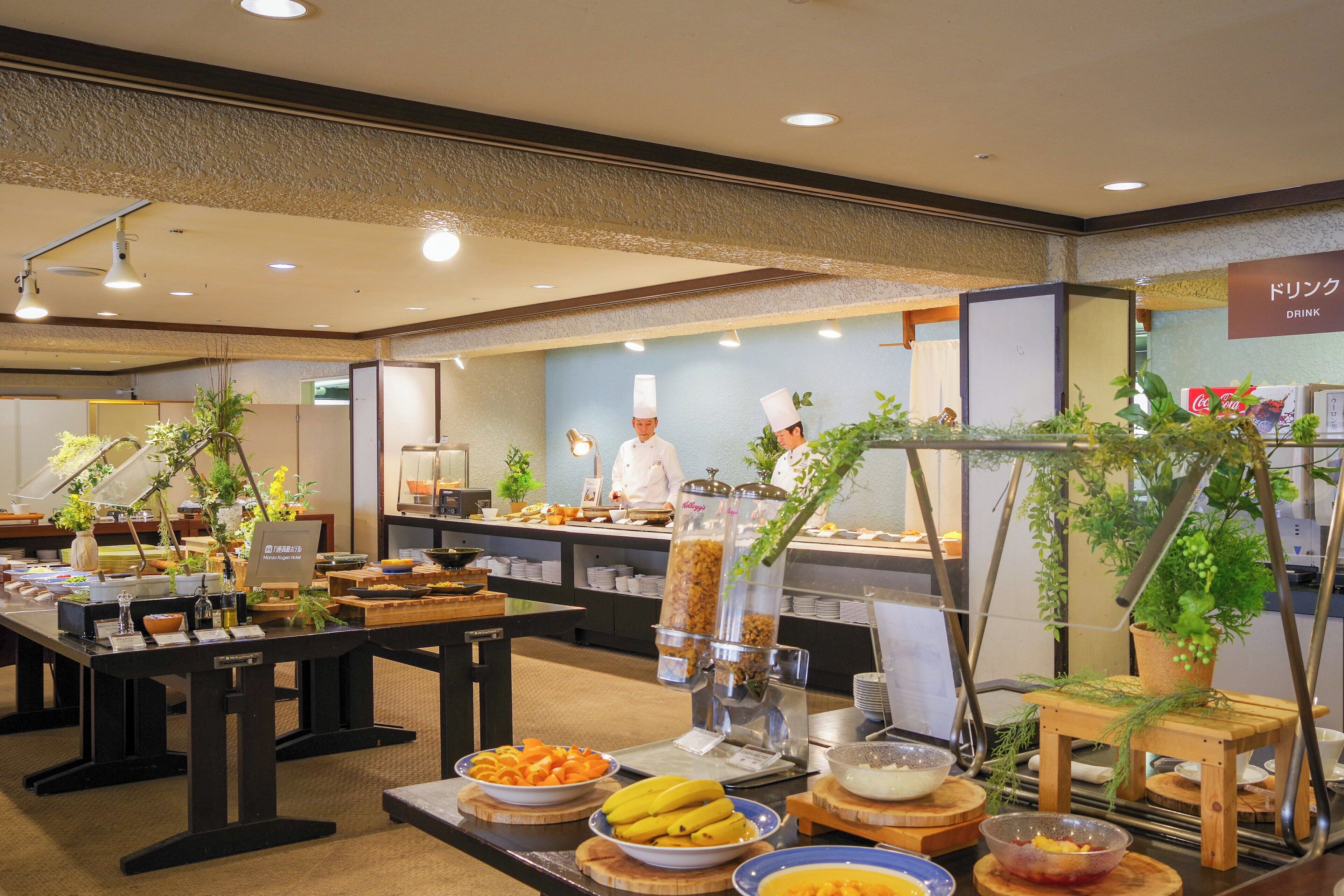 A buffet area with various food items, a coffee machine, and a sign indicating a drink station.