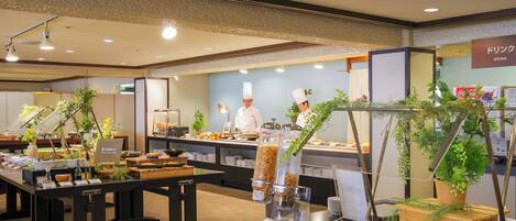 A buffet area with various food items, a coffee machine, and a sign indicating a drink station.