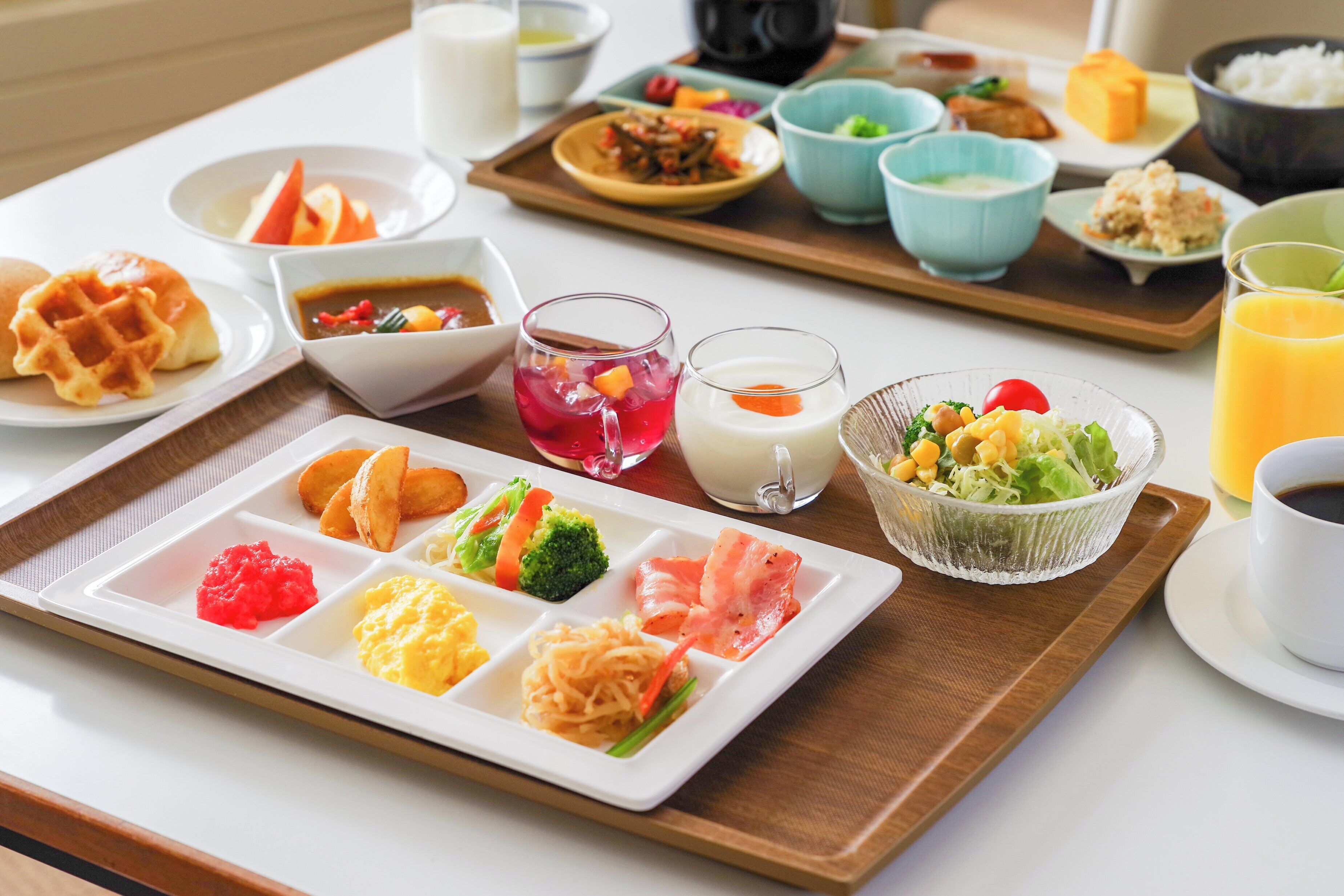 A tray with various dishes including waffles, scrambled eggs, and a salad.