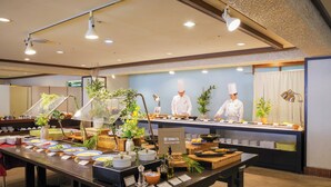 A buffet setup with multiple food stations, a chef in uniform, and a sign indicating the hotel name. - Manza Kogen Hotel (Tsumagoi)