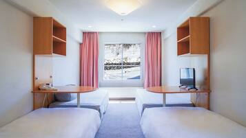 Habitación de hotel con dos camas, un escritorio, un televisor y una ventana con cortinas.