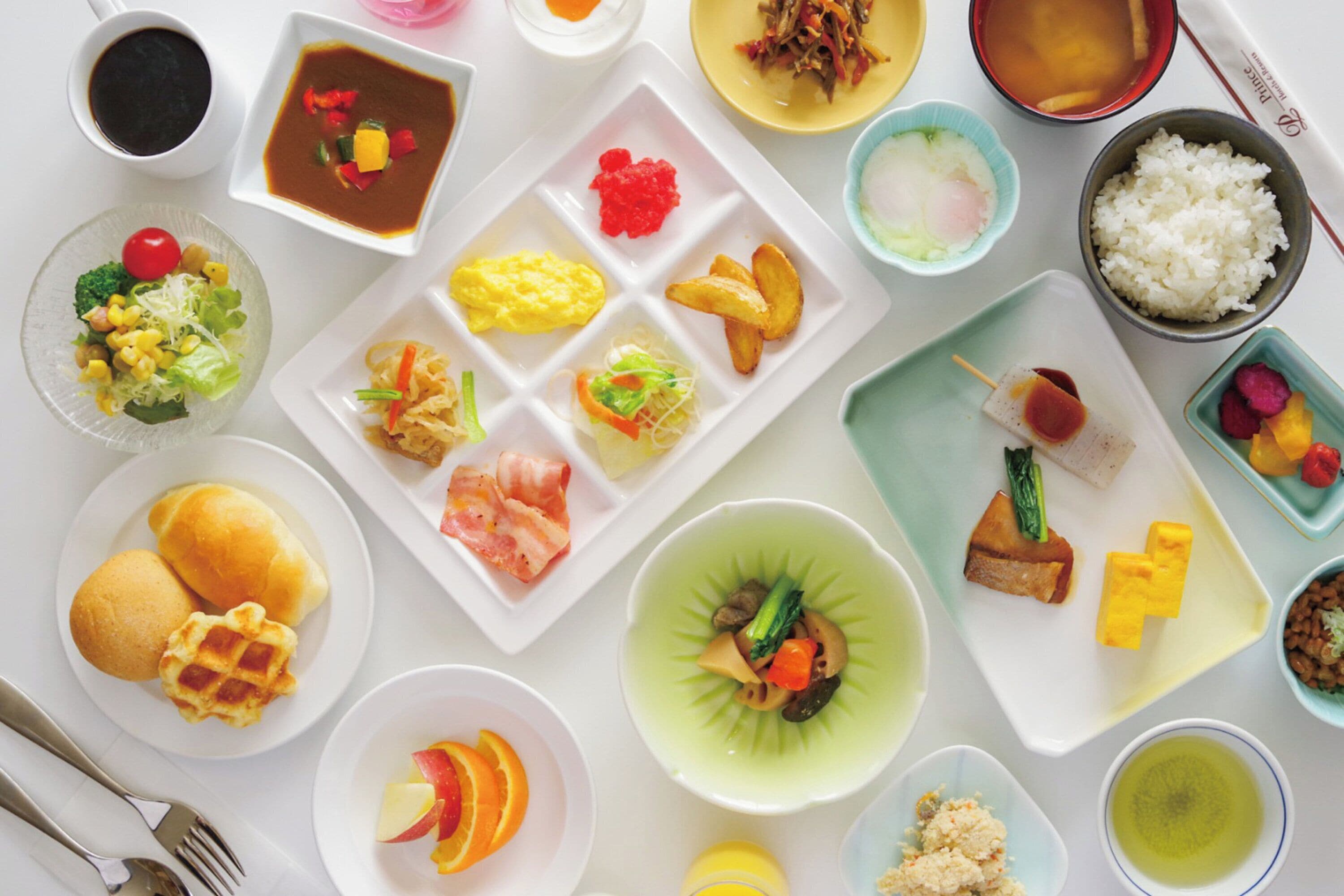 A variety of dishes including sushi, rice, and vegetables on a white table.
