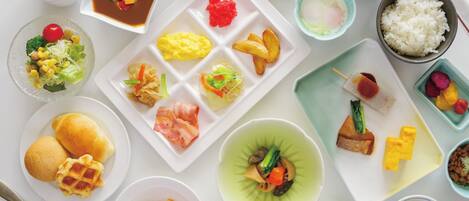 A variety of dishes including sushi, rice, and vegetables on a white table.