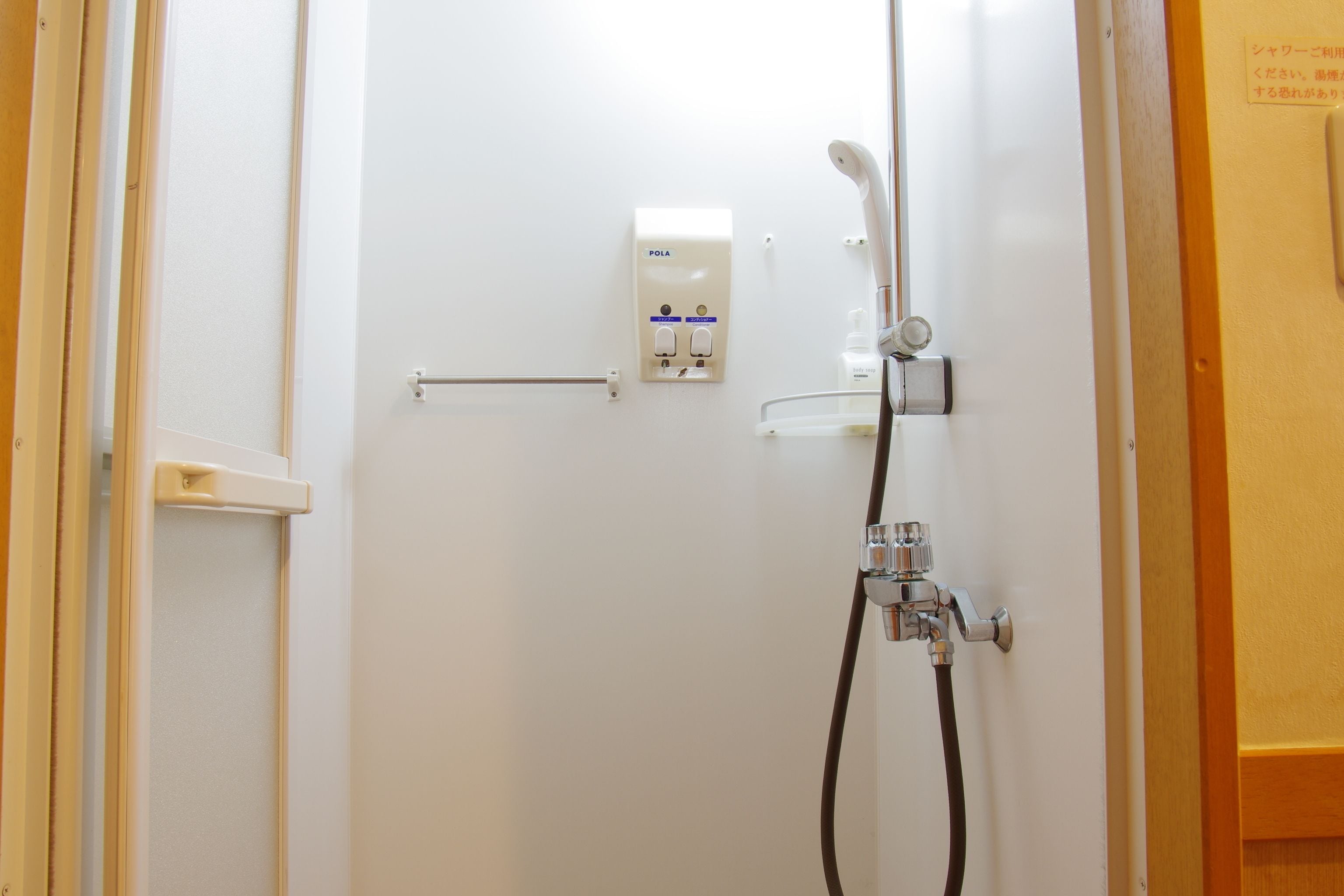 A bathroom with a shower, a hand dryer, and a towel rack.