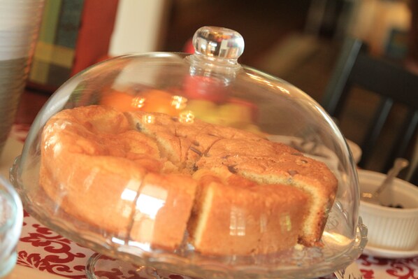 Mostrador de comida con tapa de vidrio, sobre una mesa con mantel estampado.